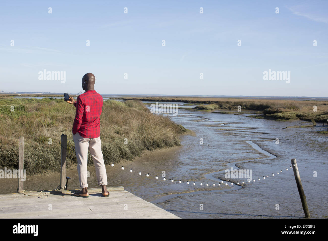 Mann steht auf Dock, Multimedia-Smartphone betrachten Stockfoto