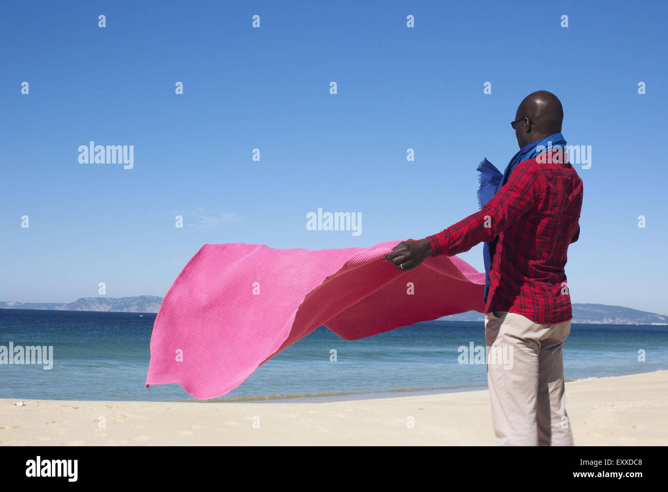 Mann am Strand, mit Decke im Wind Stockfoto