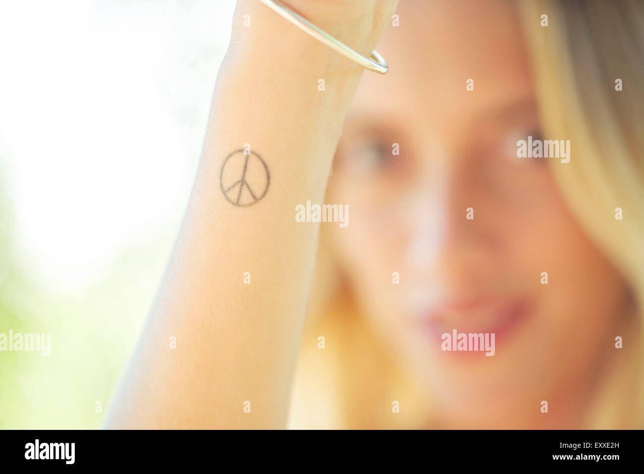 Frau mit Peace-Zeichen Tattoo an ihrem Handgelenk Stockfoto