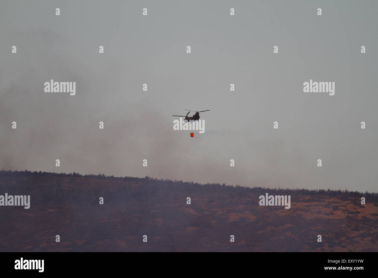 Athen, Griechenland. 17. Juli 2015. Ein Hubschrauber fliegt niedrig über die Hymettos Mountain Range in der Nähe von Athen, das Wasser auf die Waldbrände bereitzustellen. Der Rauch aus haben die Waldbrände in der Hymettos-Gebirge in der Nähe von Athen sichtbar während der Abend- und frühen Nacht abgeflaut. Die Brände jedoch weiterhin durch die Nacht zu verbrennen und sichtbar von Athen. Bildnachweis: Michael Debets/Pacific Press/Alamy Live-Nachrichten Stockfoto