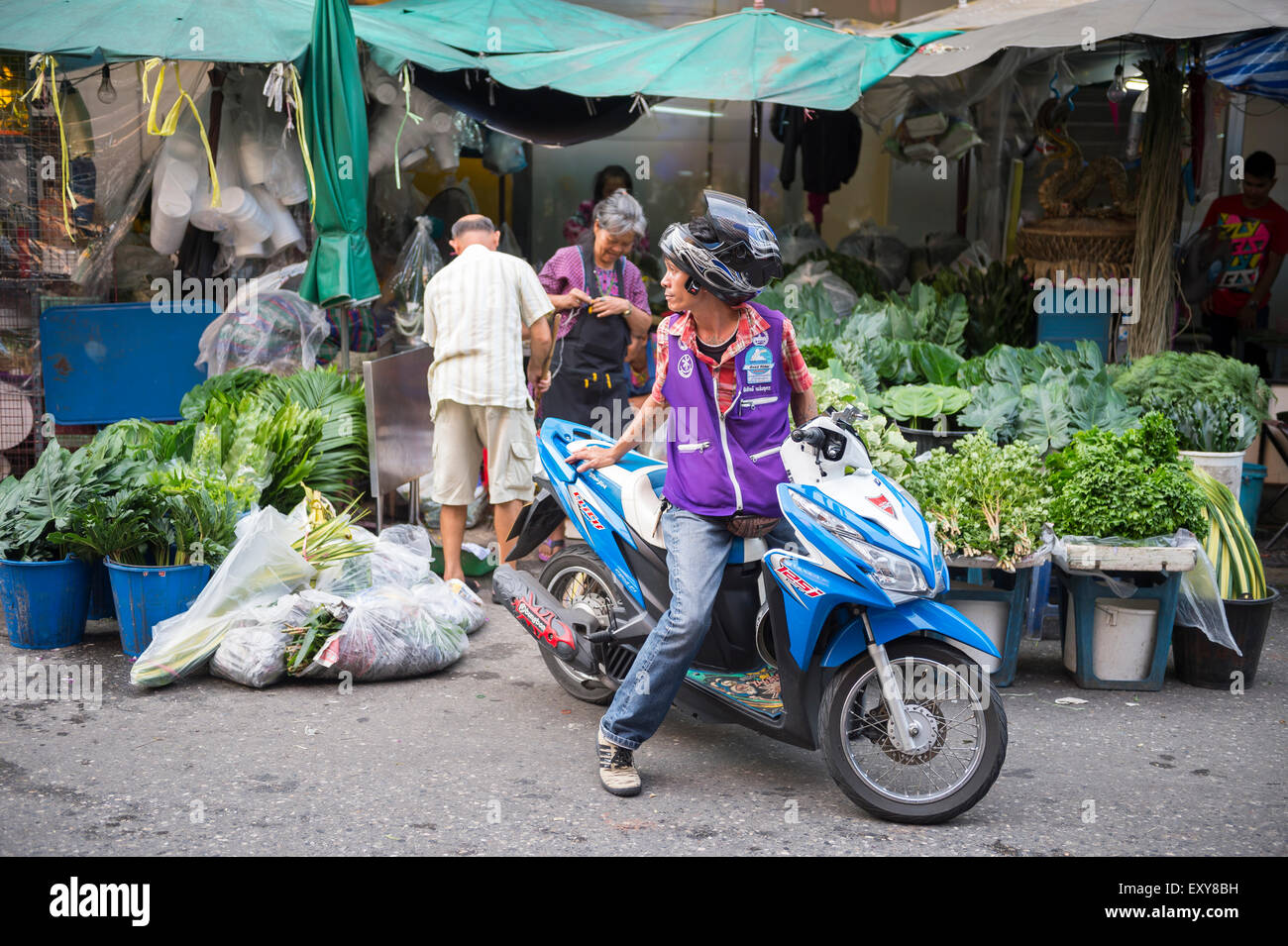 BANGKOK, THAILAND - 27. Oktober 2014: Ein Kunde zieht auf seinem Roller von einem Anbieter auf dem Markt einzukaufen. Stockfoto