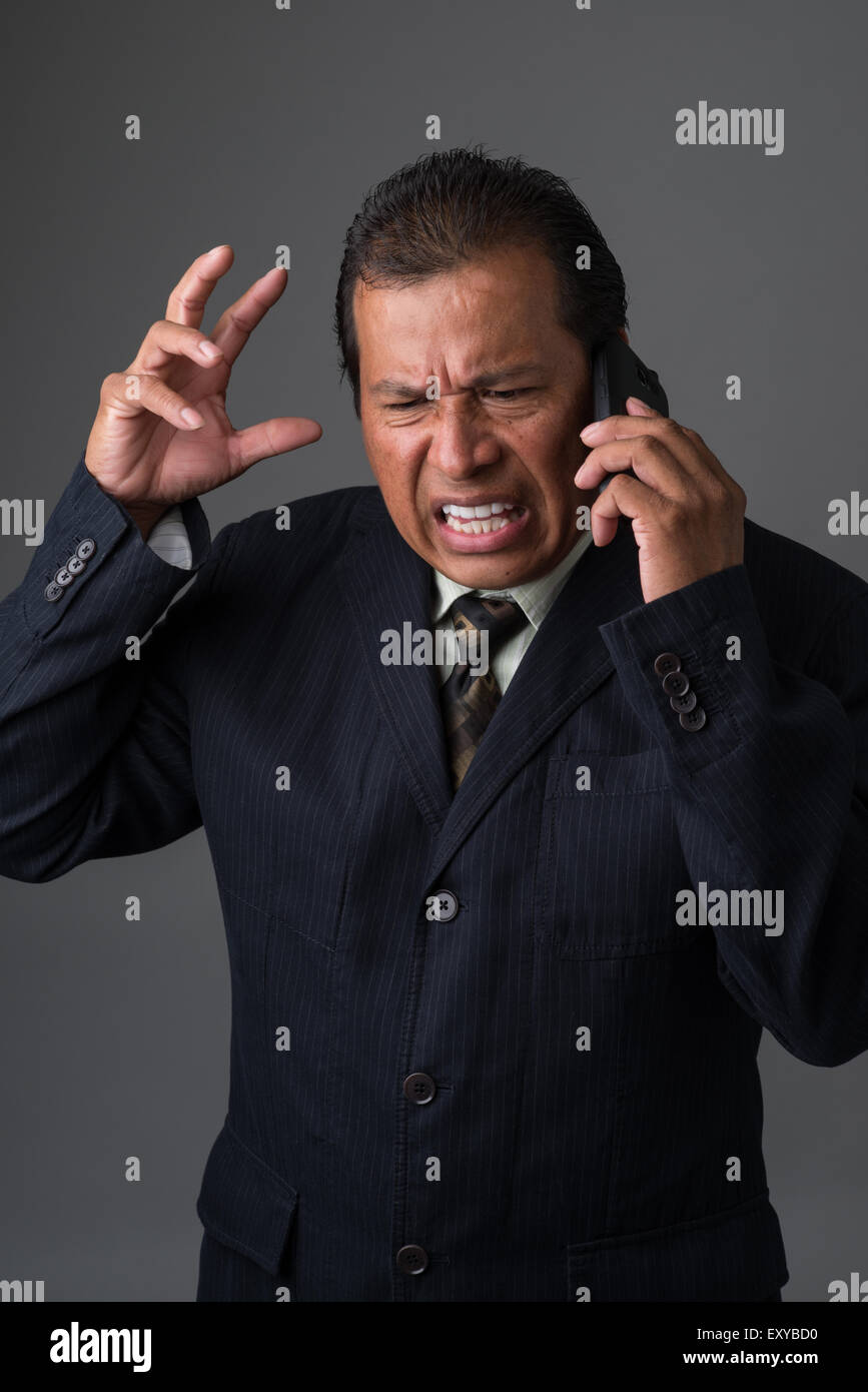 Hispanic Geschäftsmann reden auf seinem Handy, wütend und frustriert. Stockfoto