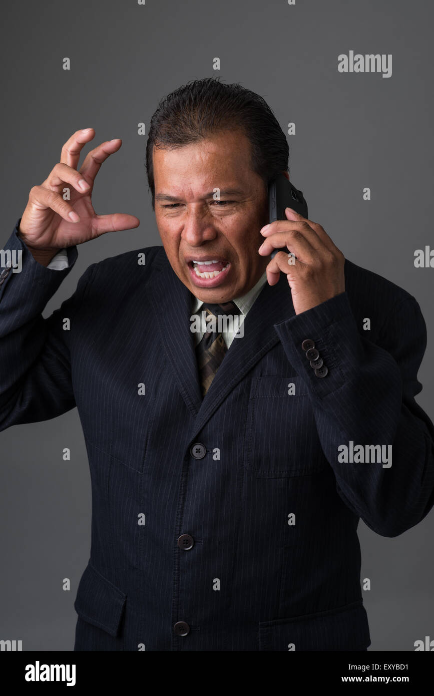 Hispanic Geschäftsmann reden auf seinem Handy, wütend und frustriert. Stockfoto