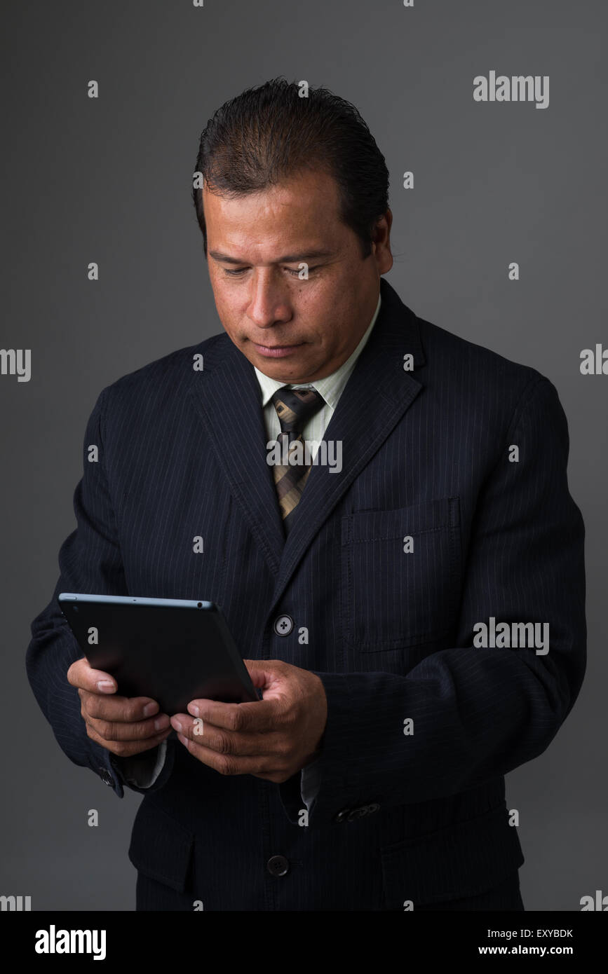 Hispanic Geschäftsmann hält ein Mini-Ipad oder Tablet, es zu lesen. Stockfoto