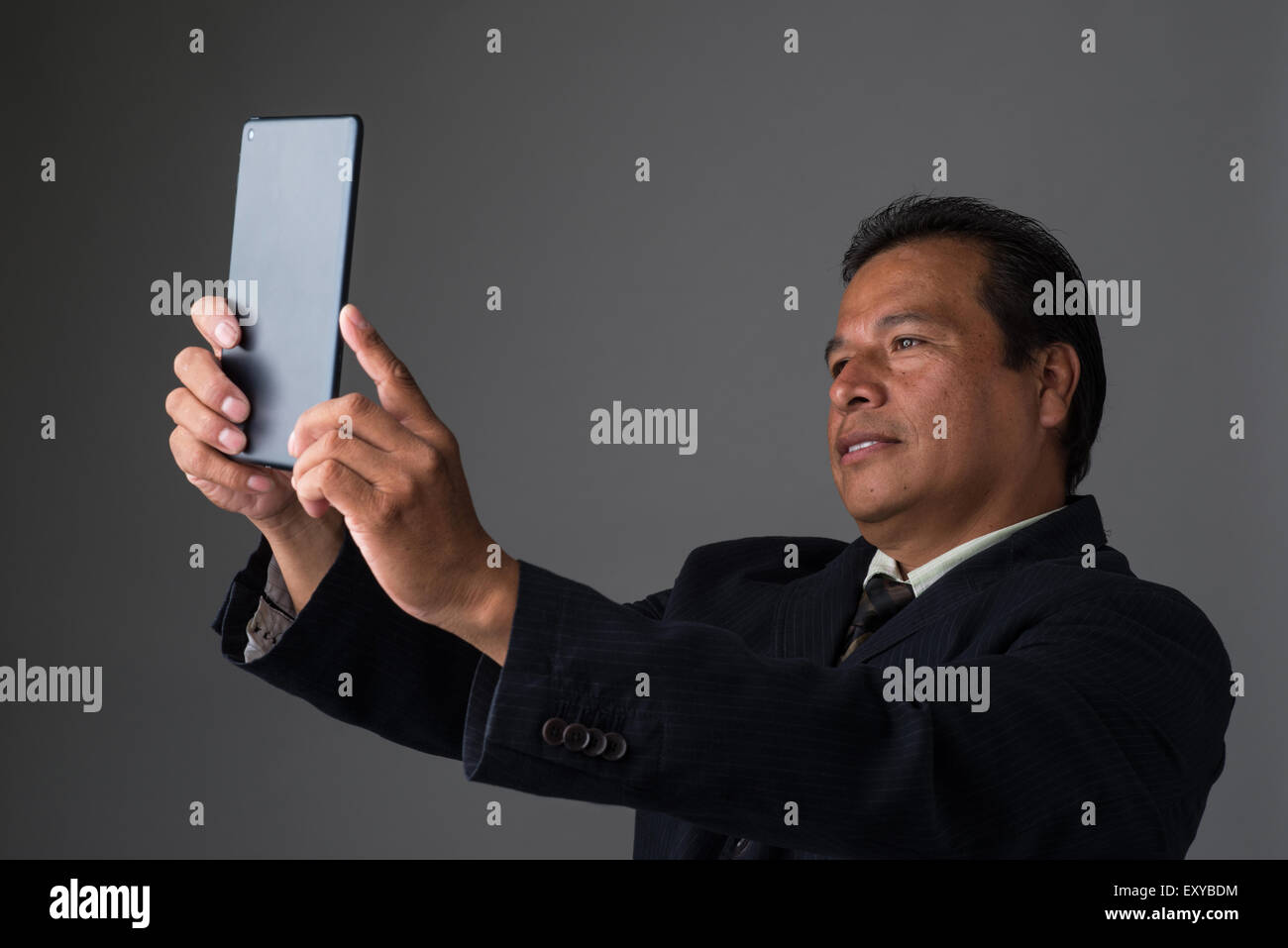 Ein Hispanic Geschäftsmann hält ein Mini-Ipad oder Tablet, wobei ein Selbstporträt. Stockfoto
