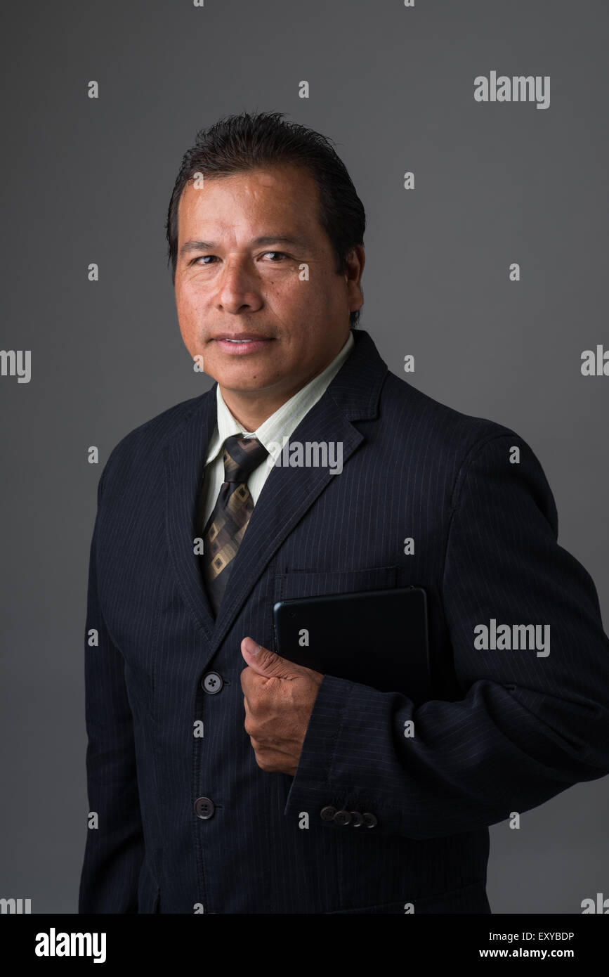 Ein Hispanic Geschäftsmann hält ein Mini-Ipad oder Tablet, posiert für ein Business-Portrait. Stockfoto