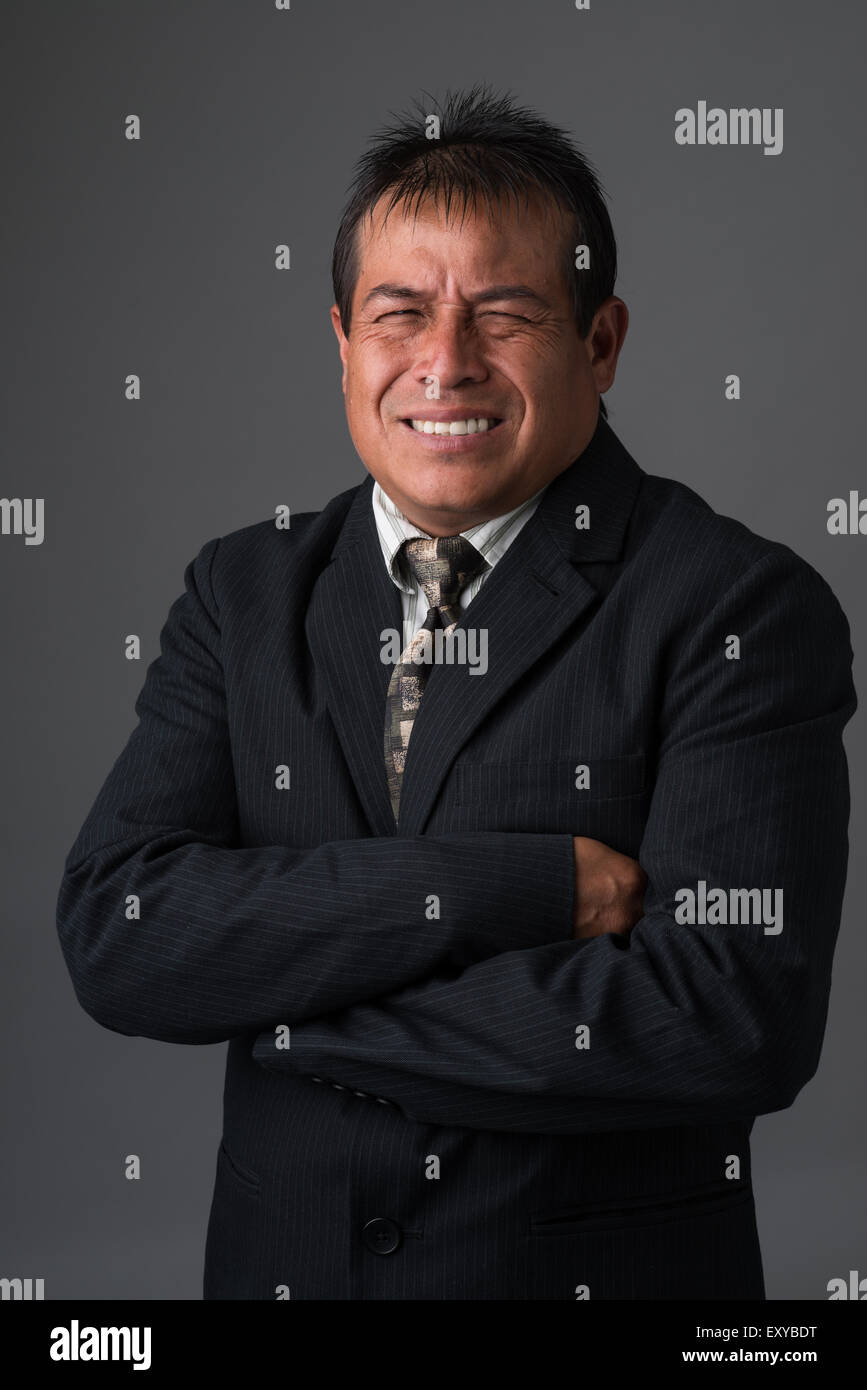 Ein Hispanic Geschäftsmann sucht frustriert, widerwillig lächelnd. Stockfoto