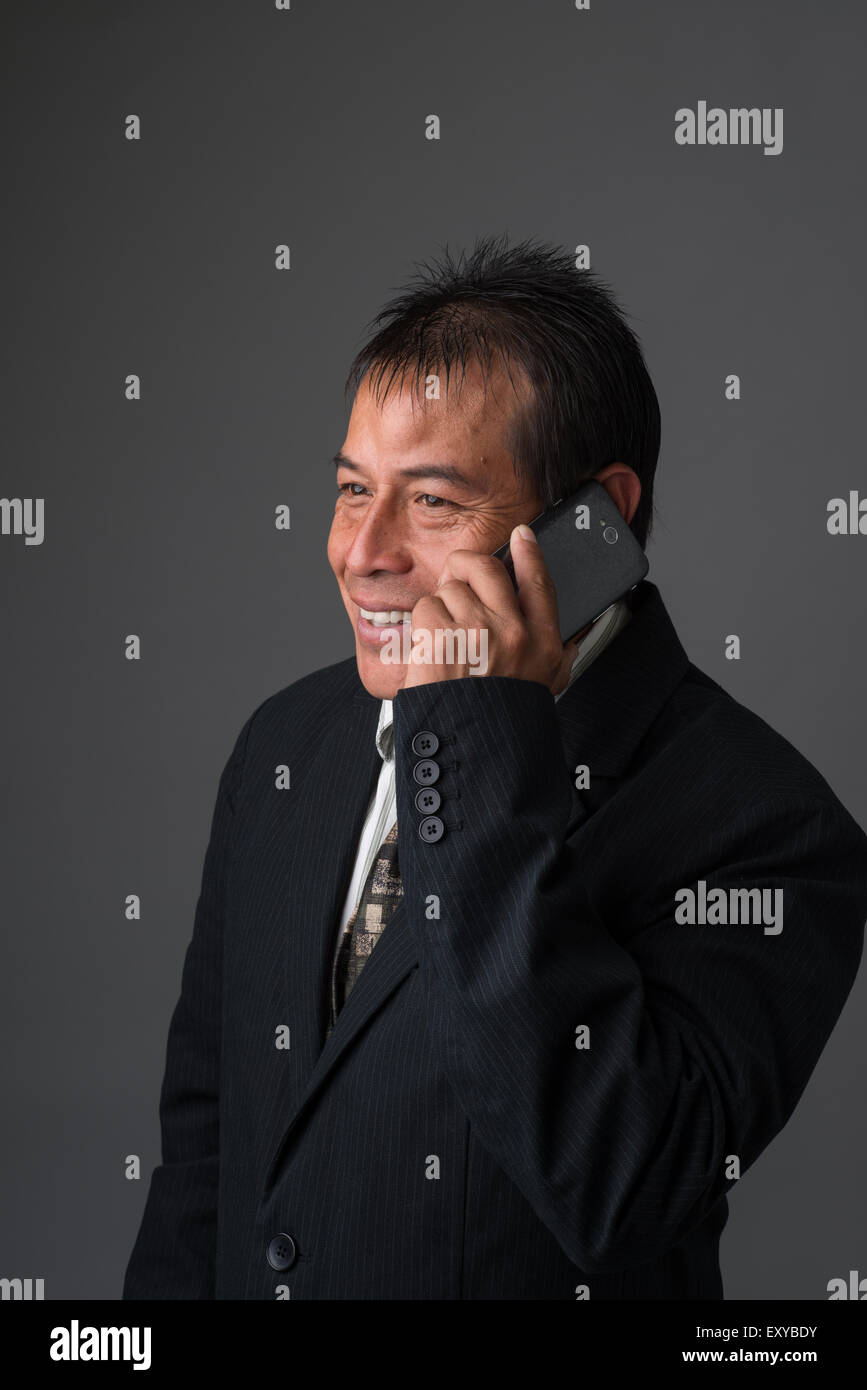 Ein Hispanic Geschäftsmann reden auf seinem Handy, lächelnd und freundlich schauen. Stockfoto