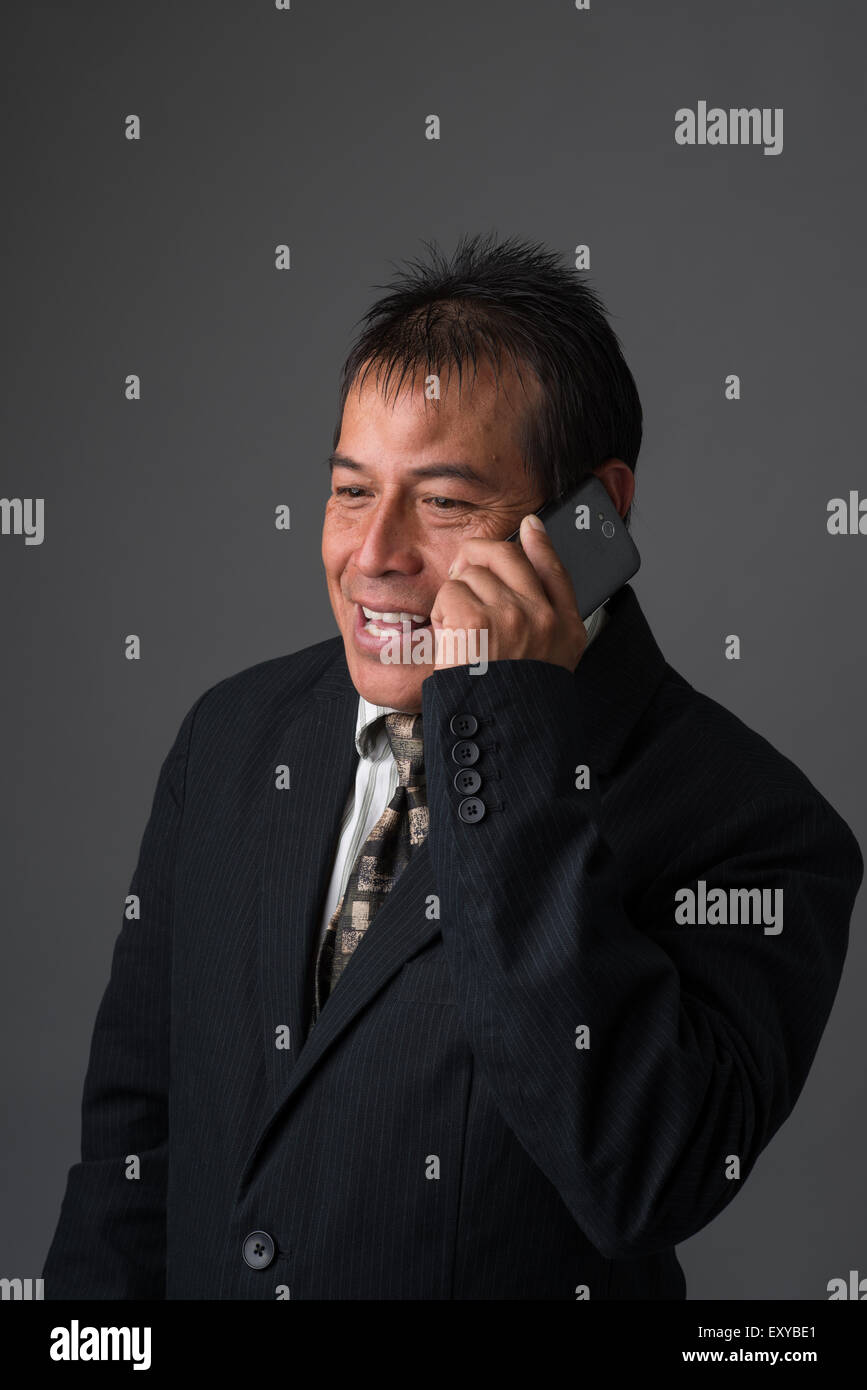 Ein Hispanic Geschäftsmann reden auf seinem Handy, lächelnd und freundlich schauen. Stockfoto