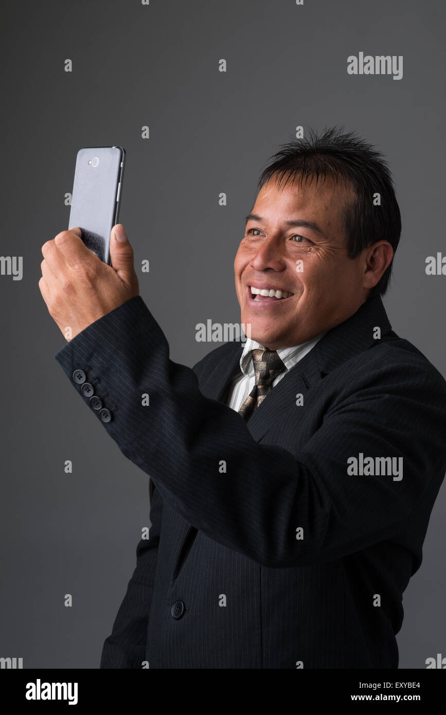 Hispanic Geschäftsmann halten, wobei ein Selbstporträt mit seinem Handy. Stockfoto