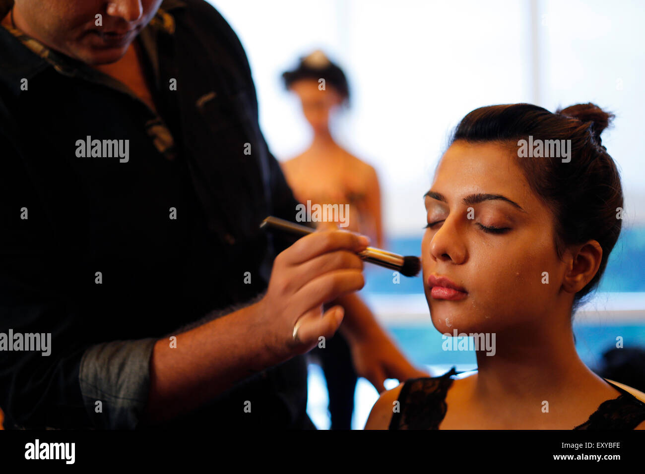 Make-up-Künstler gilt Make-up für ein Modell im Make-up-Raum hinter den Kulissen vor Beginn der Modenschau Stockfoto