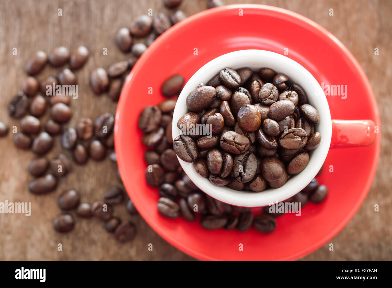 Rote Kaffeetasse mit Kaffeebohnen auf Holztisch, Fotoarchiv Stockfoto
