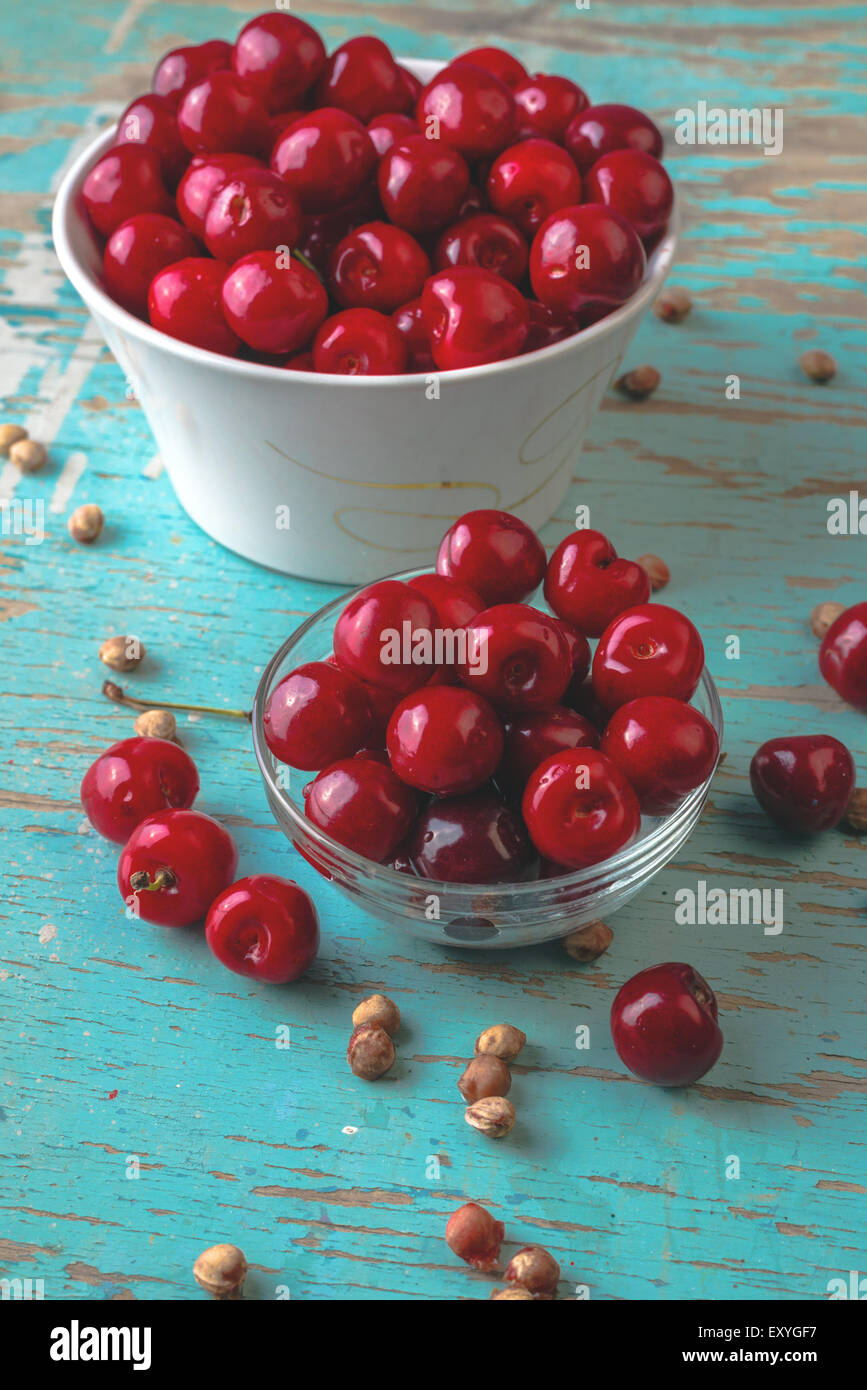 Cherry Bowl am rustikalen Tisch, Reife frische wilde Kirschen Obst und Kirschkerne Stockfoto