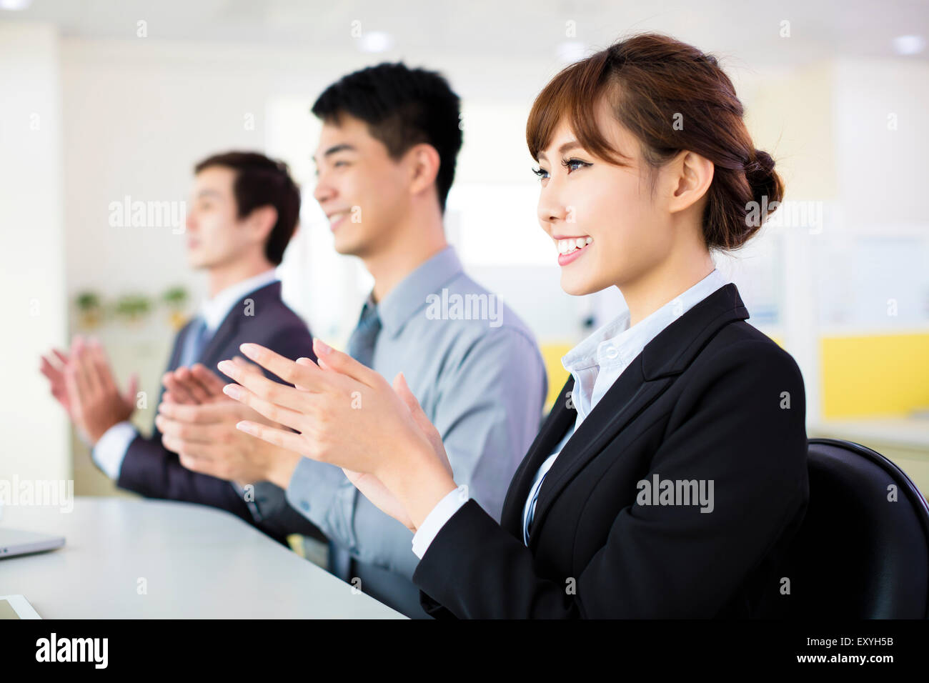 Business-Leute sitzen in einer Reihe und applaudieren Stockfoto