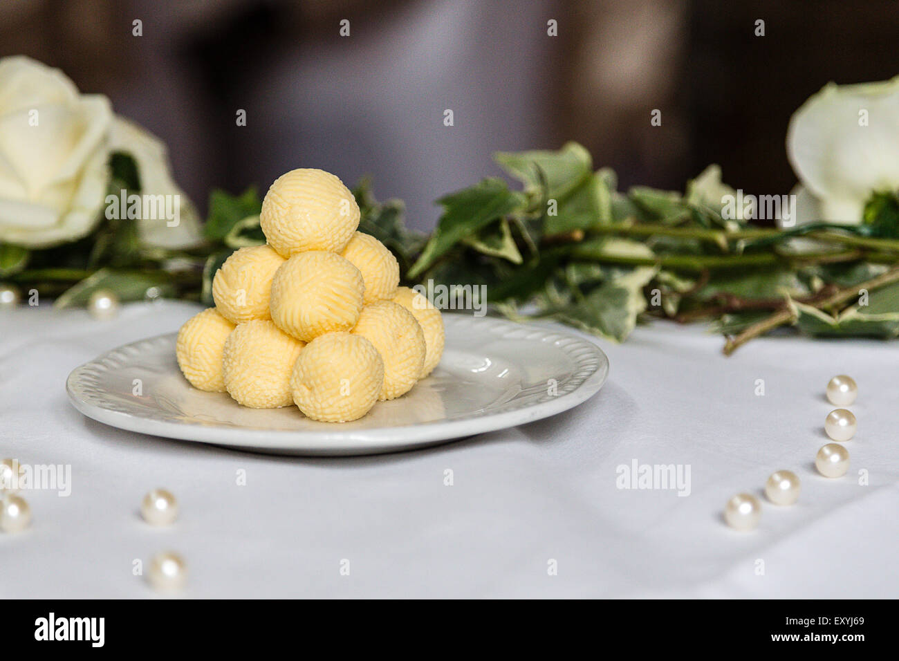Eine Pyramide von gelben Butter Kugeln auf ein gedeckter Tisch für ein Bankett. Die Kugeln werden auf Teller mit frischen Brötchen verwendet werden serviert. Stockfoto