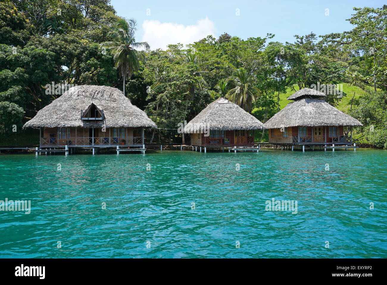 Tropische Küste mit strohgedeckten Bungalows über dem Wasser an der karibischen Küste von Panama, Bocas del Toro, Mittelamerika Stockfoto