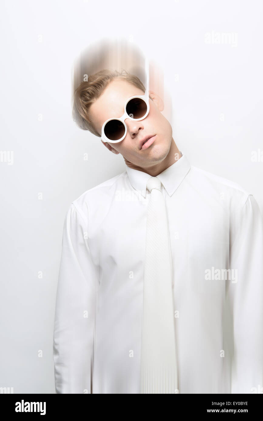 Ein junger Mann, männliches Model trägt ein alle weißen Outfit und Runde Sonnenbrille posiert, Kopf kippen. Eine futuristische Modekonzept! Stockfoto