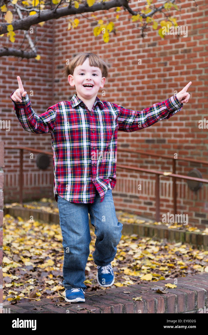 Kleiner Junge tanzt auf Ziegelmauer Stockfoto