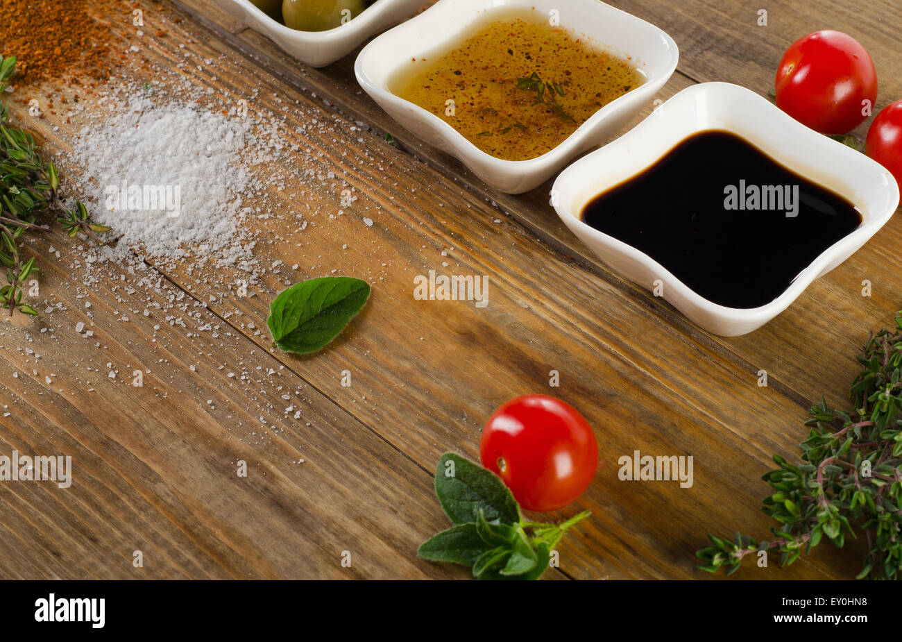 Dressing Zutaten auf rustikalen hölzernen Hintergrund. Olivenöl, Balsamico-Essig, Kräuter, Salz und Pfeffer. Selektiven Fokus Stockfoto