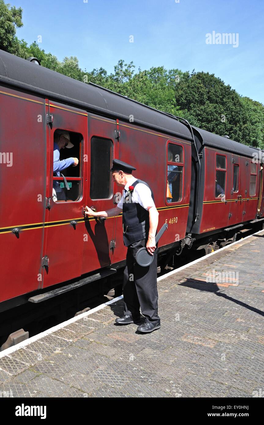 Träger neben der LMS/British Rail Maroon Eisenbahnwagen bereit, Passagiere aussteigen, Highley, England, Vereinigtes Königreich zu helfen. Stockfoto