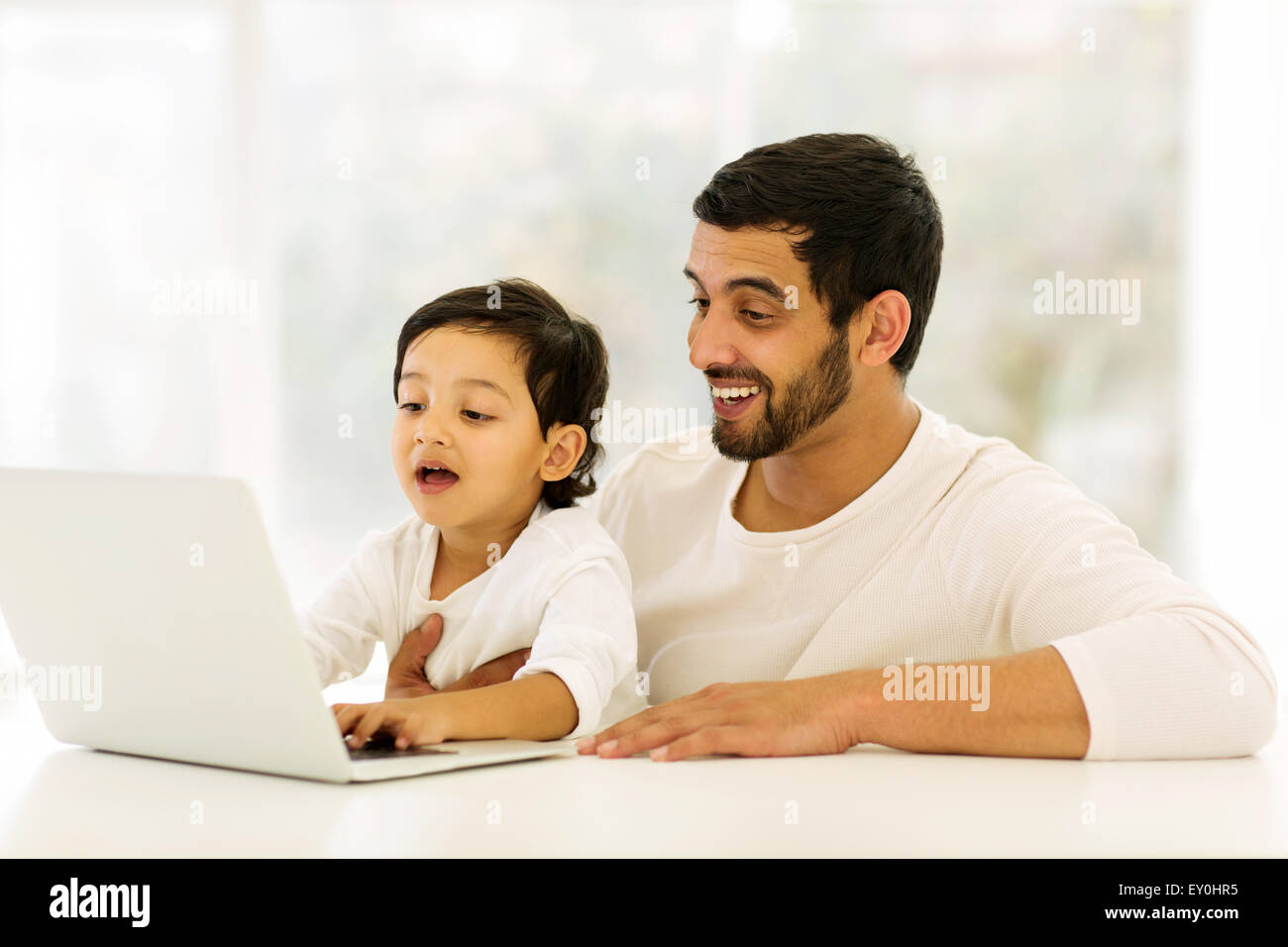 niedliche kleine Indianerjunge mit Laptop mit seinem Vater zu Hause Stockfoto
