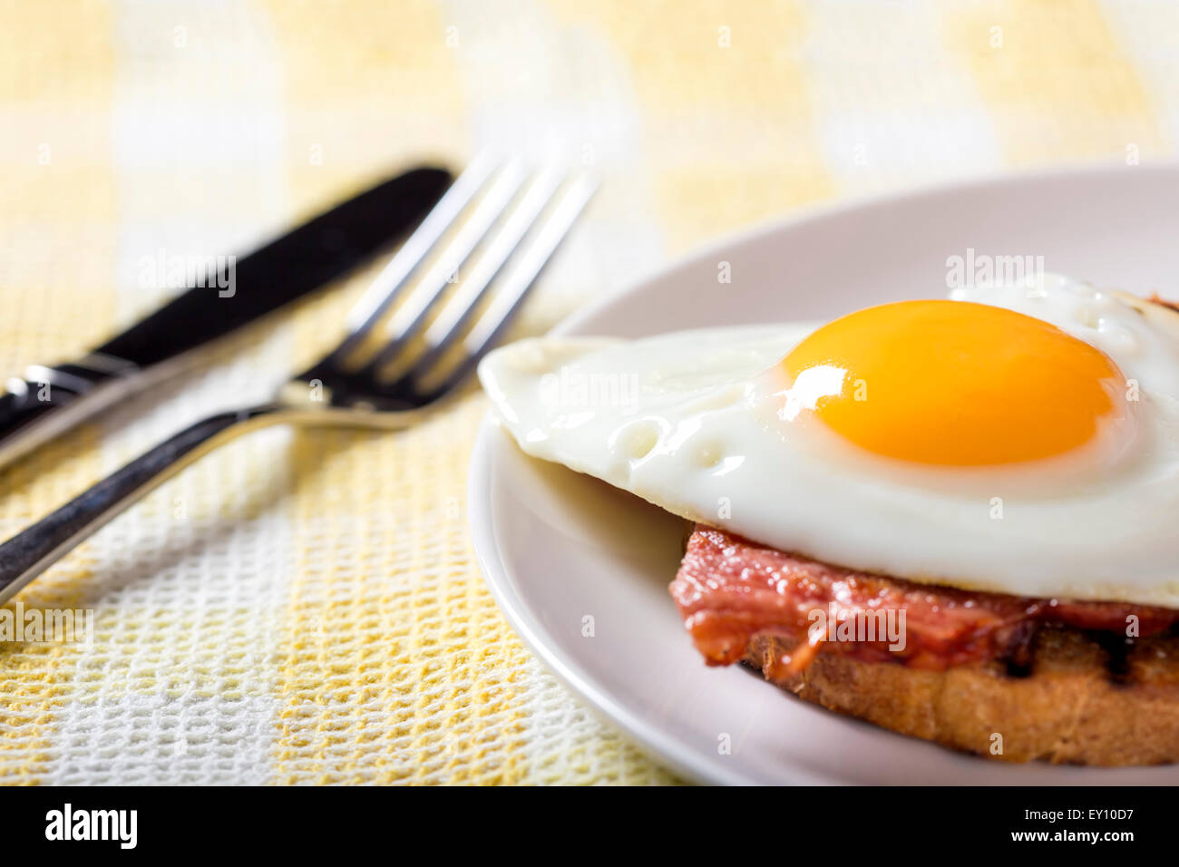 Toast mit Spiegeleiern und Speck auf einem weißen Teller Stockfoto