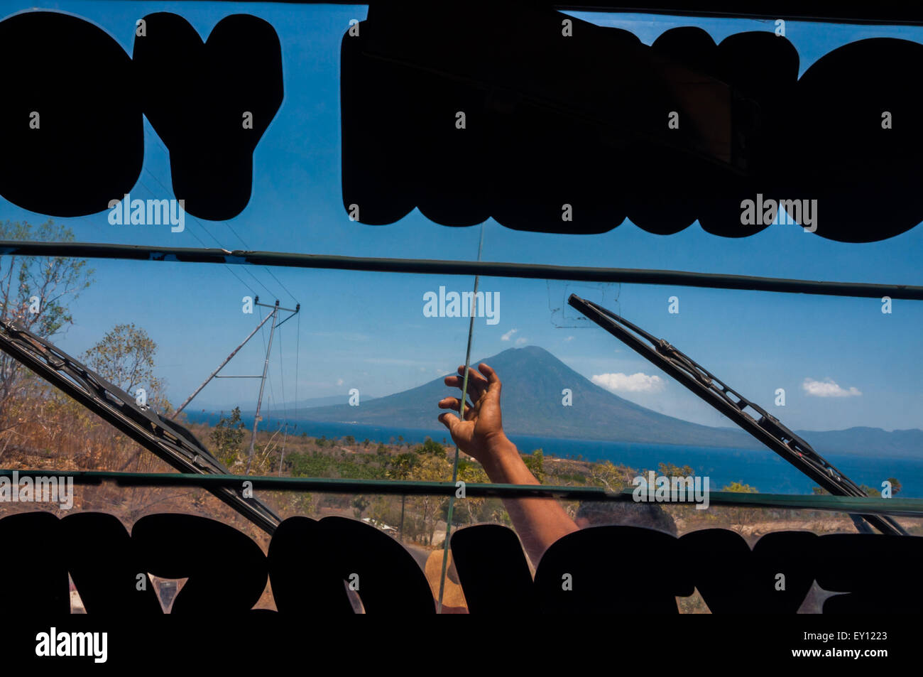 Der Boleng auf der Insel Adonara, die Boleng-Straße und die Hand eines Buspersonals werden von einem Bus aus gesehen, der auf einer Straße auf der Insel Lembata, Indonesien, hält. Stockfoto
