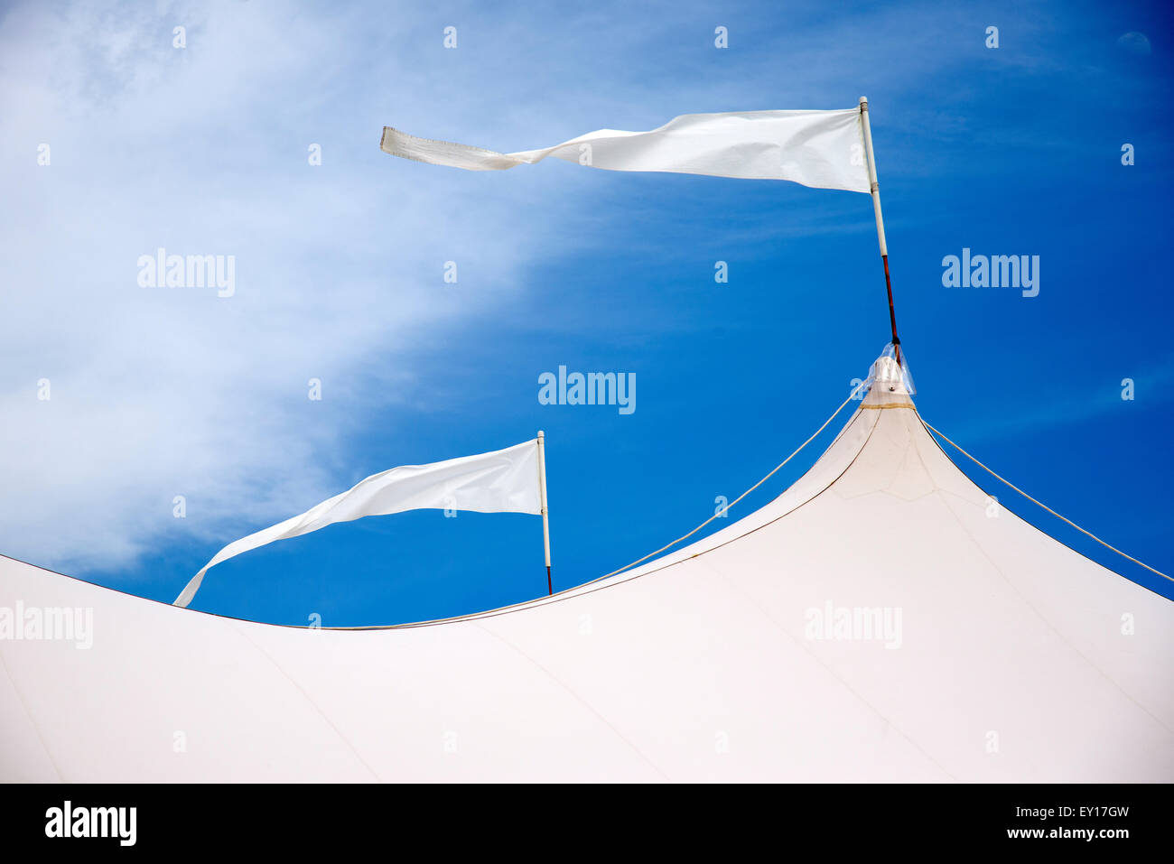 Zelt-Dach mit weißen Fahnen im Wind vor blauem Himmel Stockfoto Zelt-Dach mit weißen Fahnen im Wind vor blauem Himmel Stockfoto