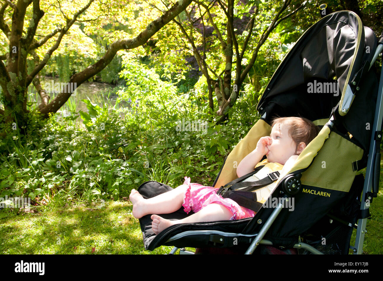 Babymädchen in ihrem Kinderwagen im Freien ihre Daumenlutschen Stockfoto