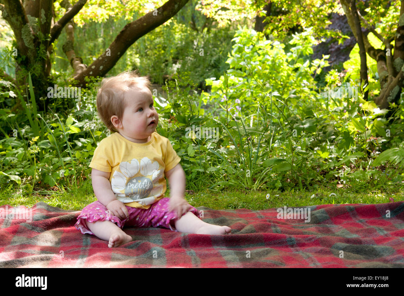 Babymädchen sitzt auf einem Teppich im Freien ohne fremde Hilfe Stockfoto