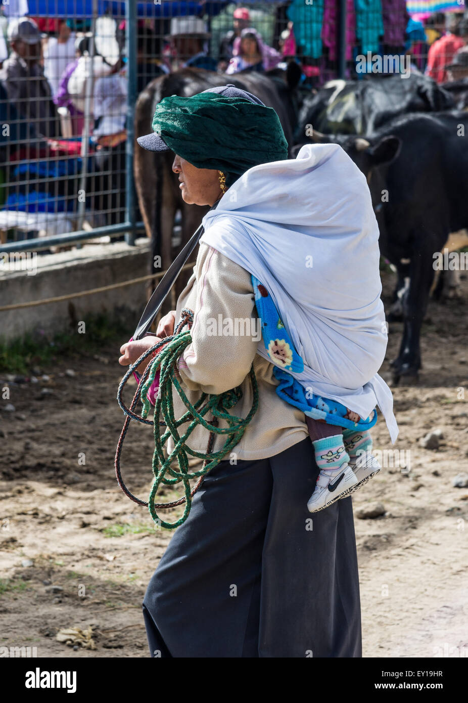 Eine Frau trägt ein Baby auf dem Rücken am Viehmarkt. Otavalo, Ecuador. Stockfoto