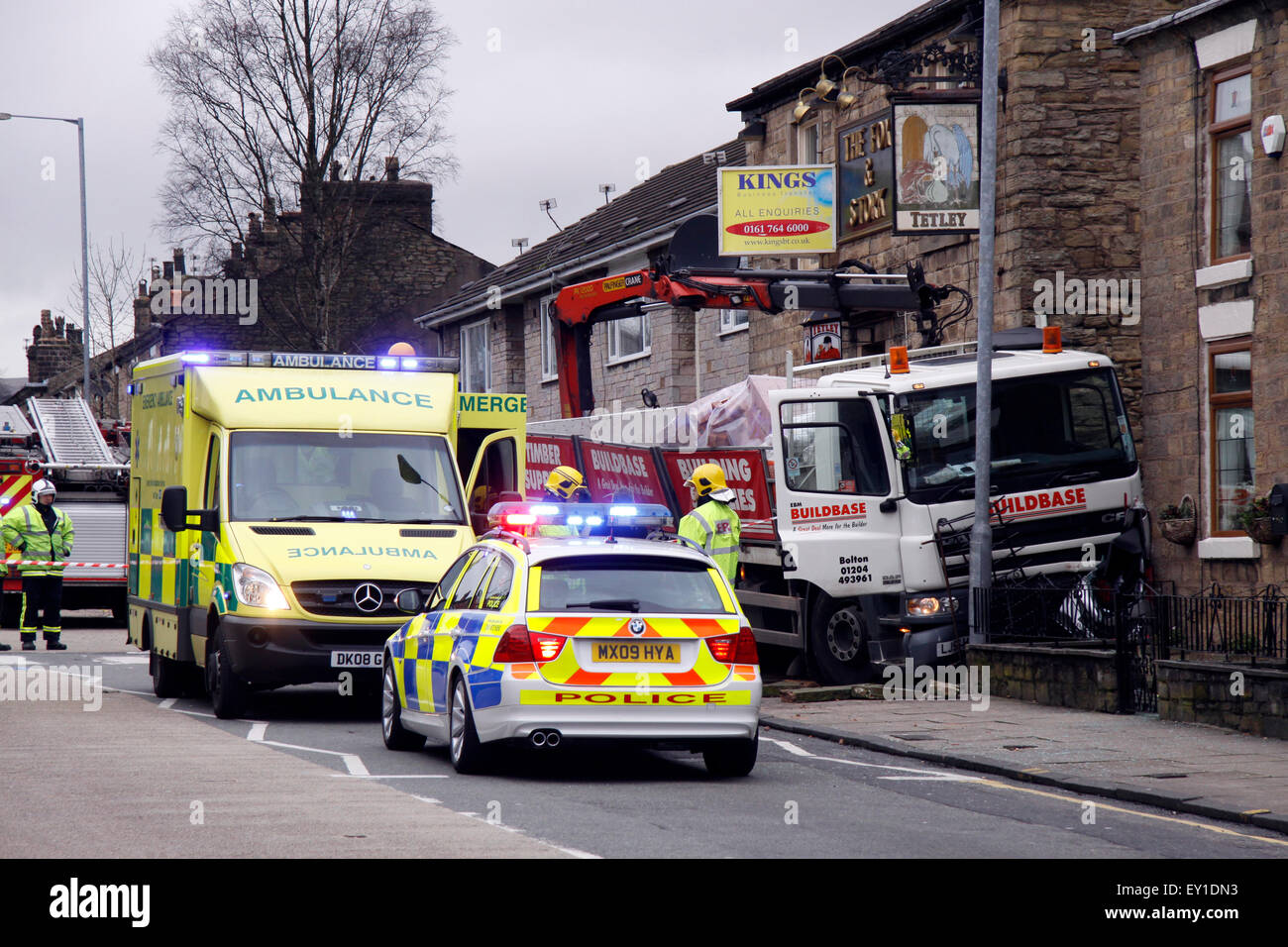 LKW beladen mit schweren Bau Materialien Reittiere der Fahrbahn stürzt in ein Wirtshaus und Zerkleinern von einem geparkten Auto in Großbritannien Stockfoto