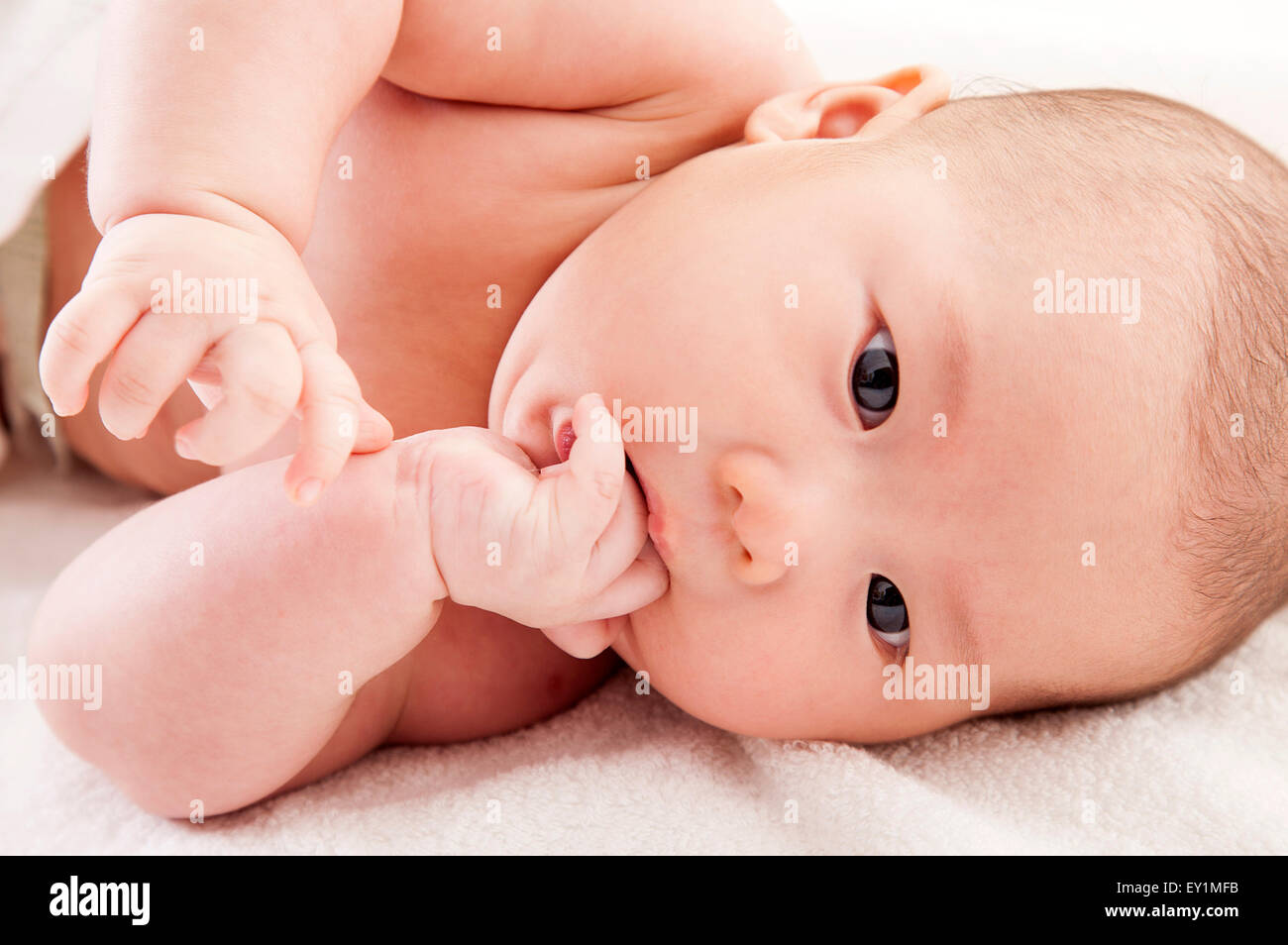 Baby Junge liegen auf Seite mit Finger im Mund, Stockfoto