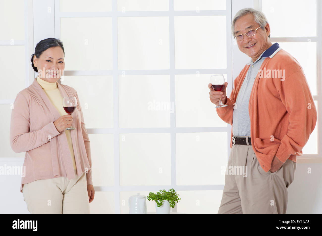 Älteres Paar mit einem Glas Rotwein und lächelt in die Kamera, Stockfoto