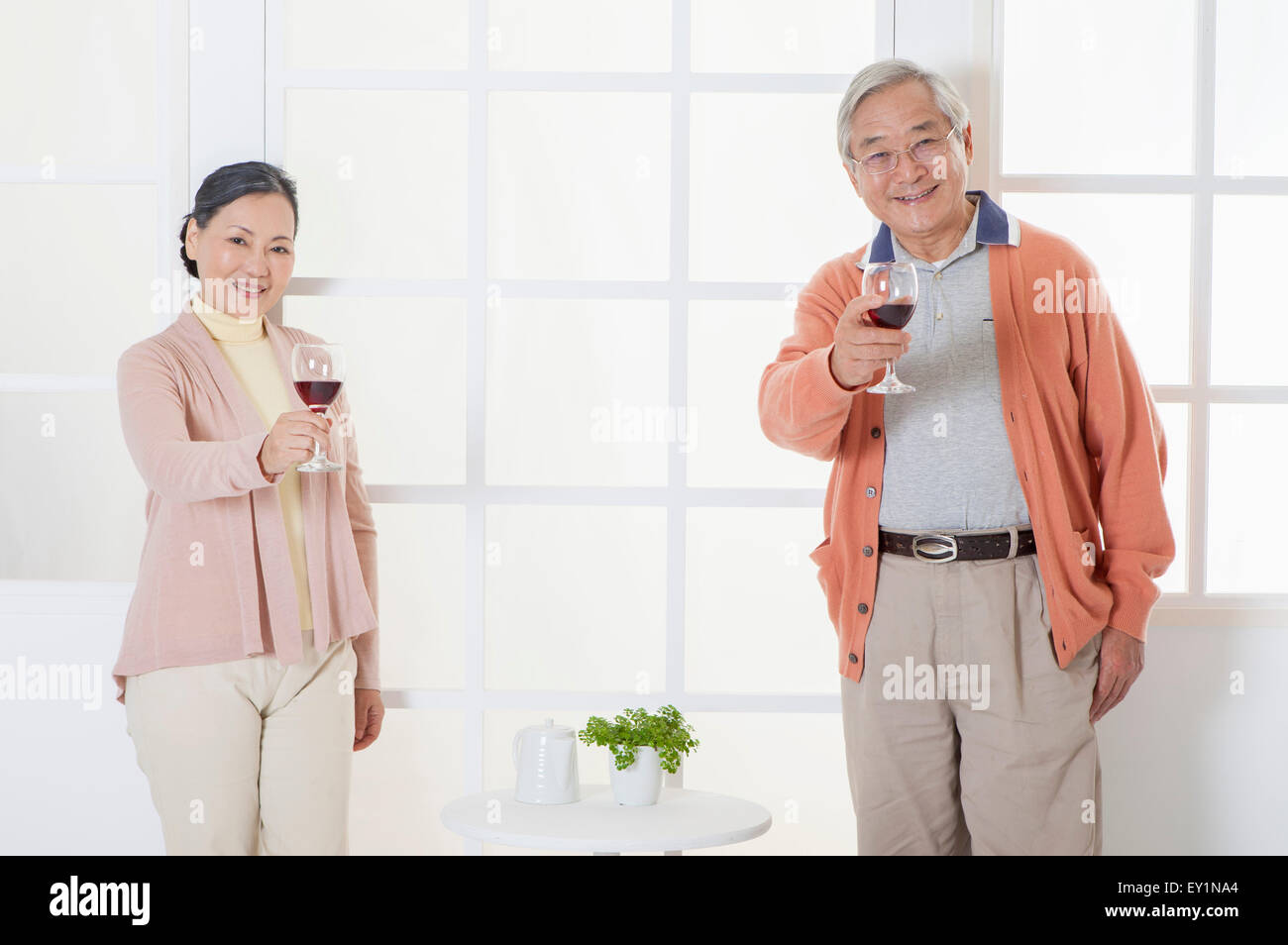 Älteres Paar mit einem Glas Rotwein und lächelt in die Kamera, Stockfoto
