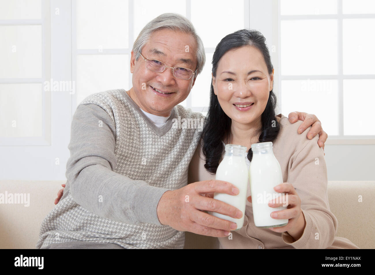 Älteres Paar eine Flasche Milch und lächelt in die Kamera halten, Stockfoto
