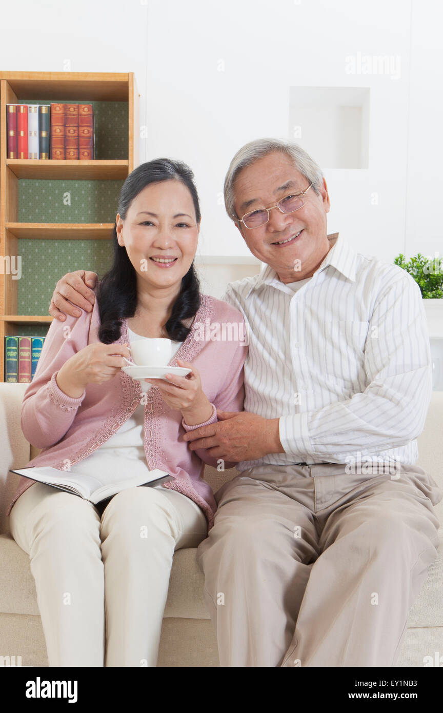 Älteres Paar auf Sofa sitzen und gerne in die Kamera Lächeln, Stockfoto