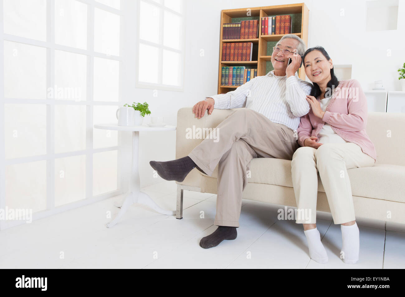 Älteres Paar auf dem Sofa sitzen und wegschauen mit Lächeln, Stockfoto