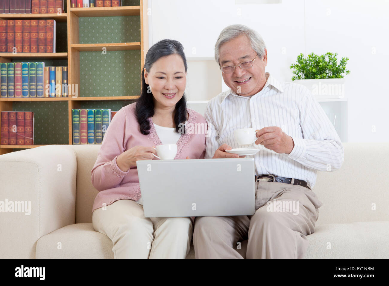 Älteres Paar hält eine Tasse trinken und Blick auf den Laptop zusammen, Stockfoto