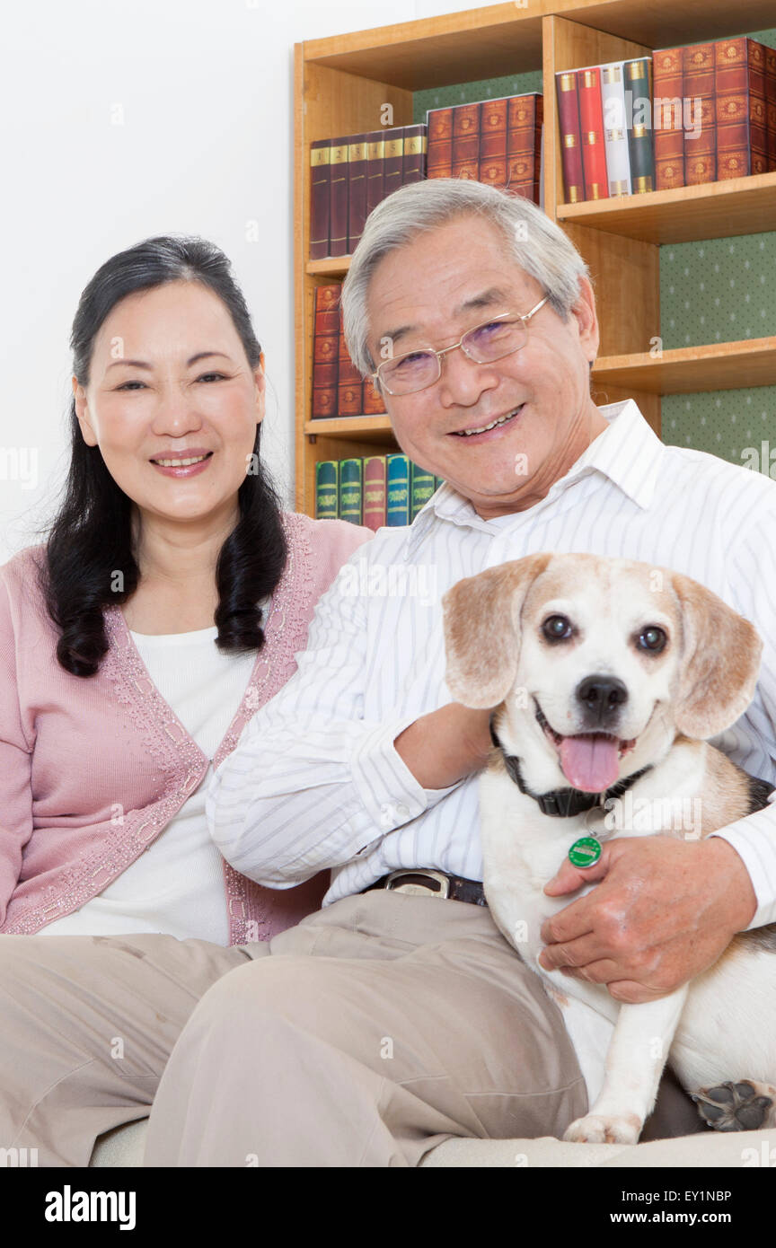 Älteres Paar glücklich lächelnd in die Kamera mit einem Hund, Stockfoto