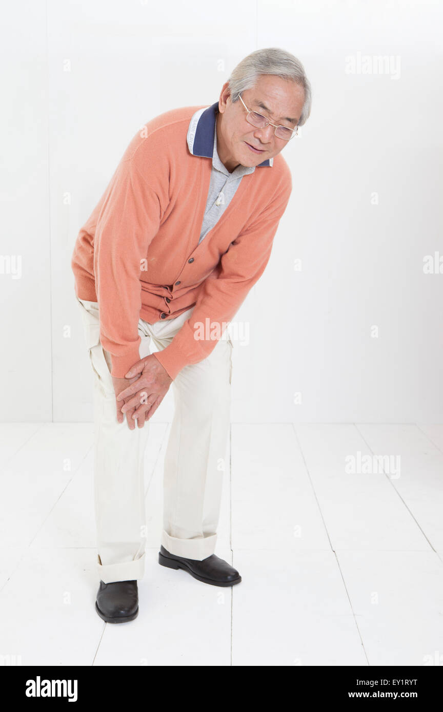 Ältere Mann mit Schmerzen auf die Knie mit schmerzhaften Gesichtsausdruck, Stockfoto