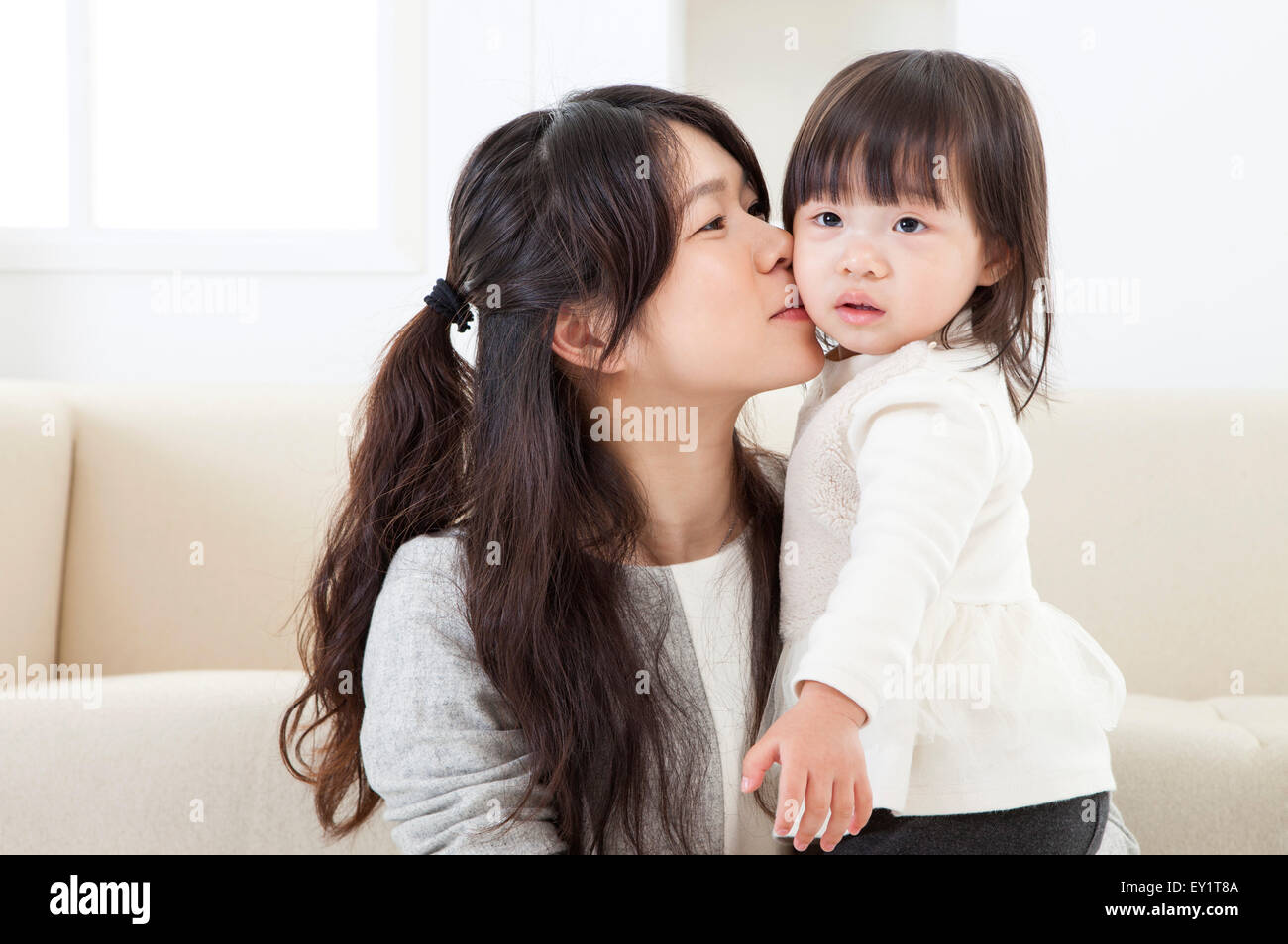 Mutter Babymädchen küssen und wegsehen, Stockfoto