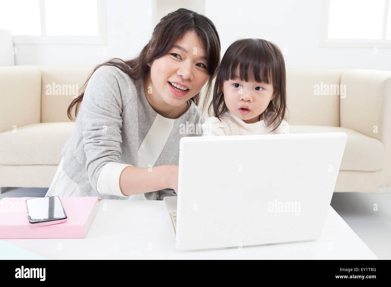 Mutter und Baby Mädchen berühren Laptop und lächelnd, Stockfoto