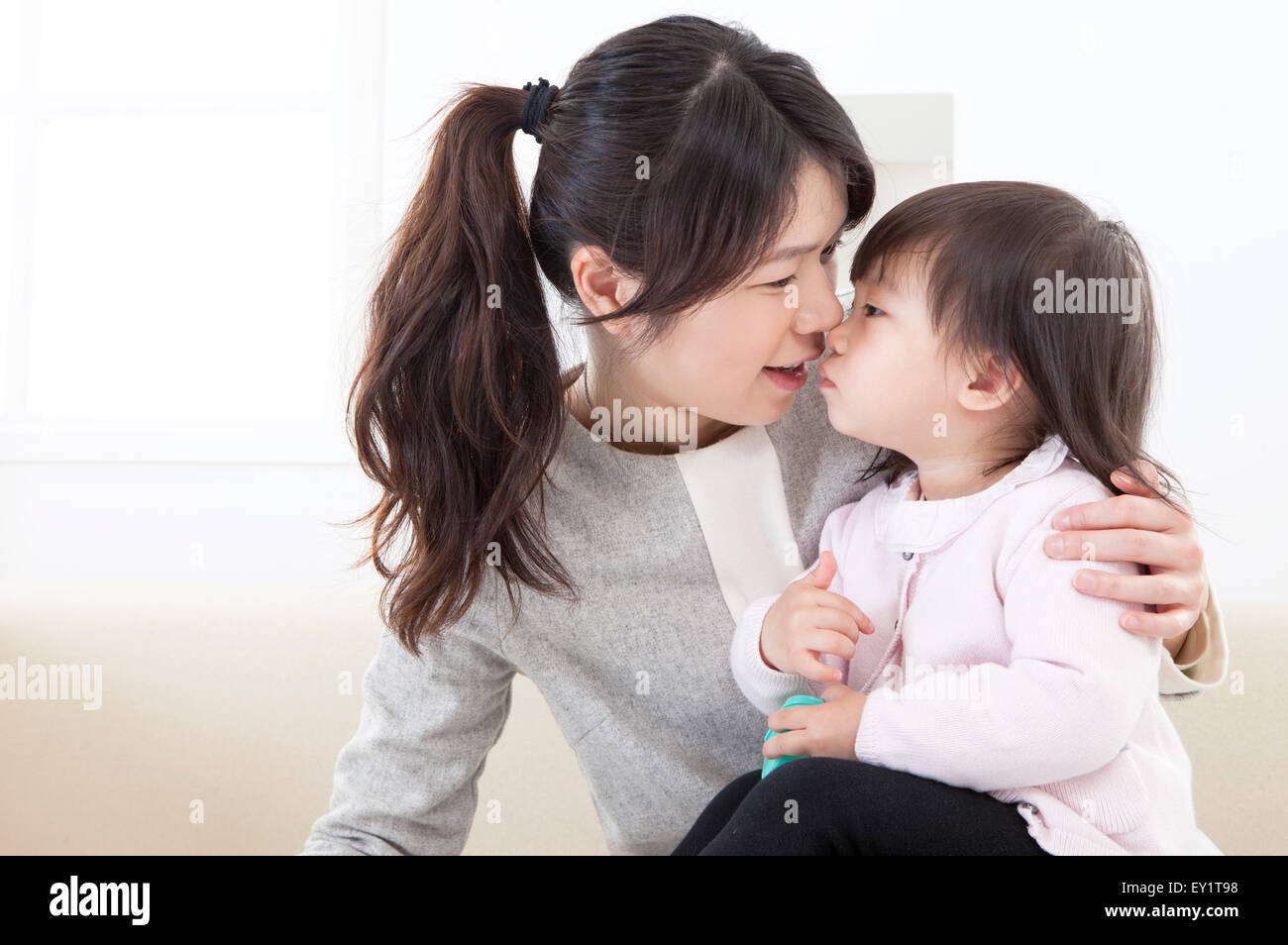 Mutter küssen Babymädchen mit Lächeln, Stockfoto