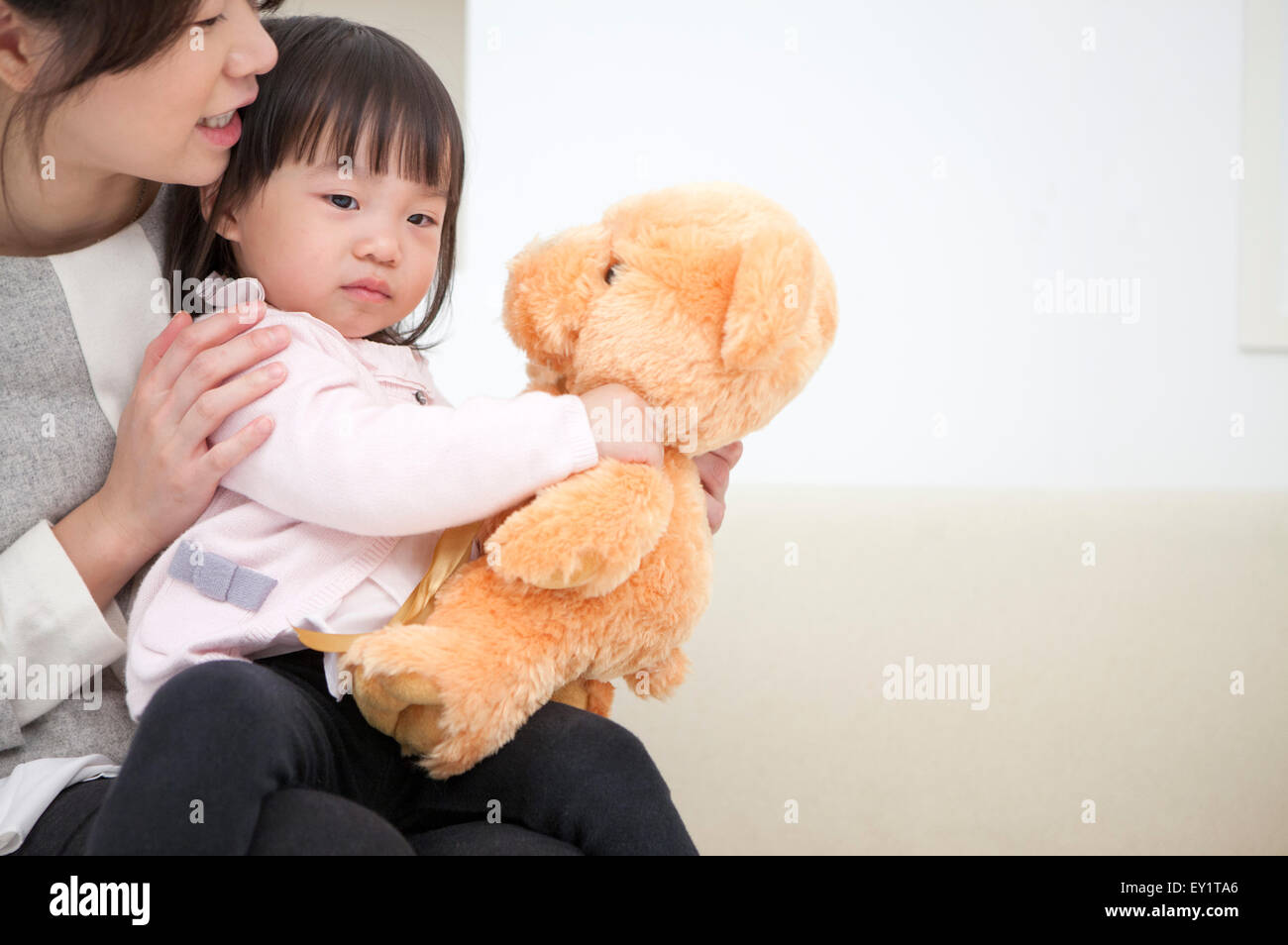 Mutter und Baby Mädchen spielen Teddybär, Stockfoto