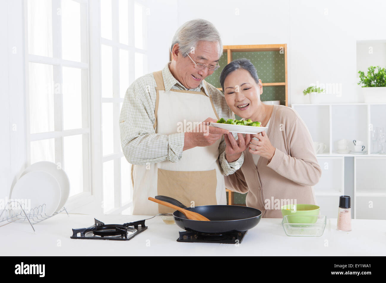 Älteres Paar hält eine Schüssel in der Küche mit Lächeln zusammen, Stockfoto