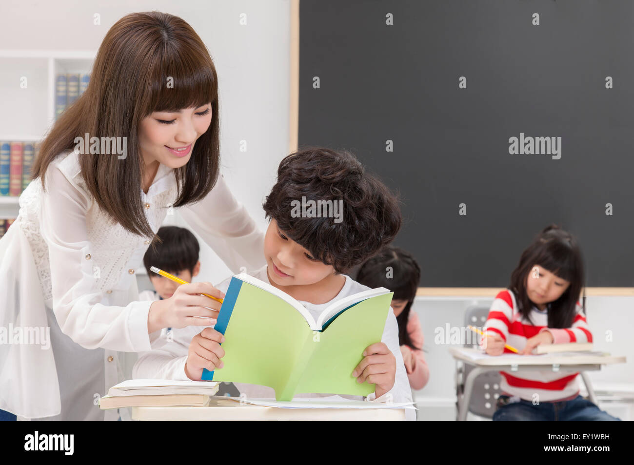 Junge Lehrer und Schüler lesen ein Buch mit Anleitung, Stockfoto