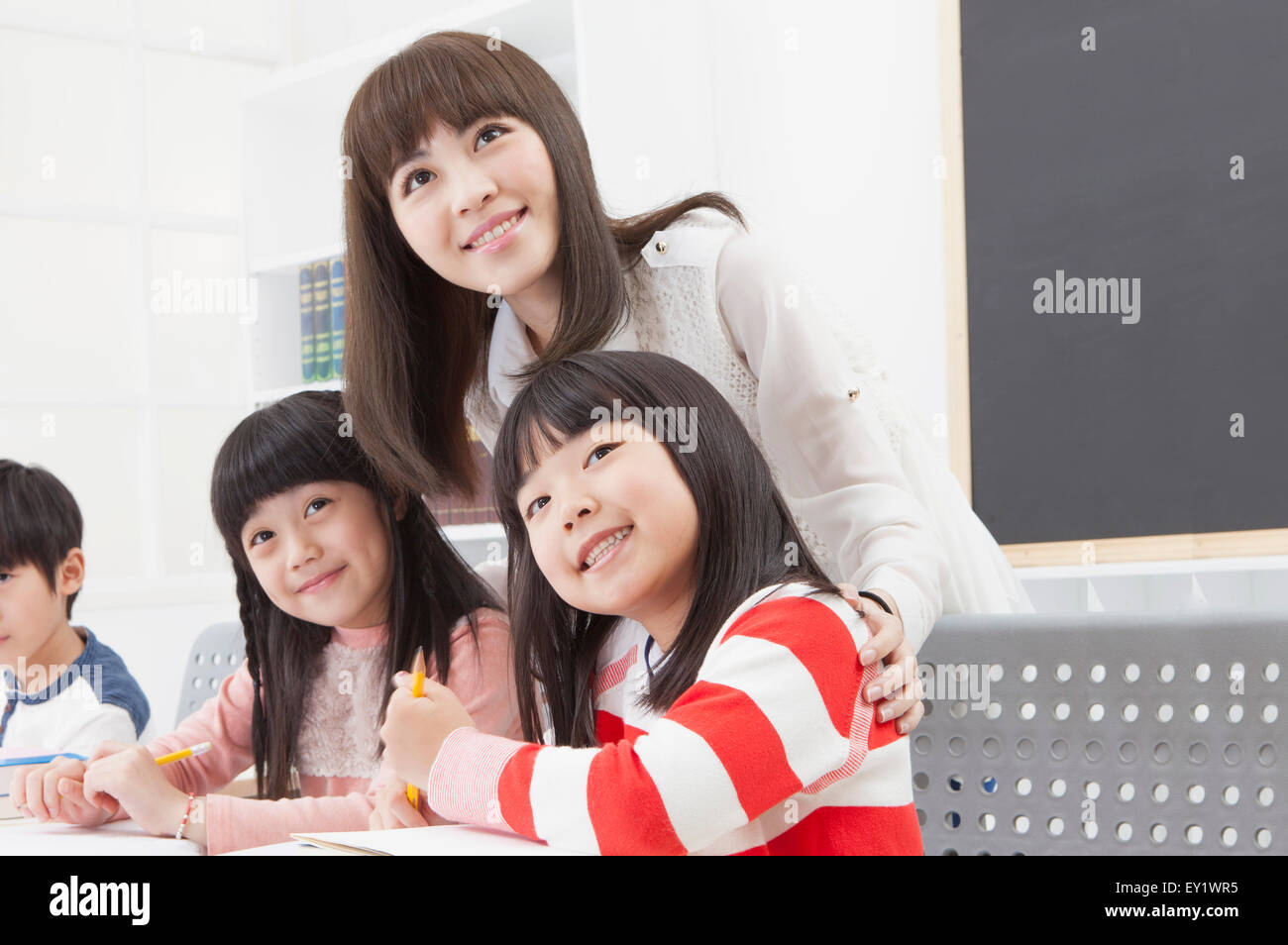 Junge Lehrer unterrichten von Schülern im Klassenzimmer und lächelnd, Stockfoto