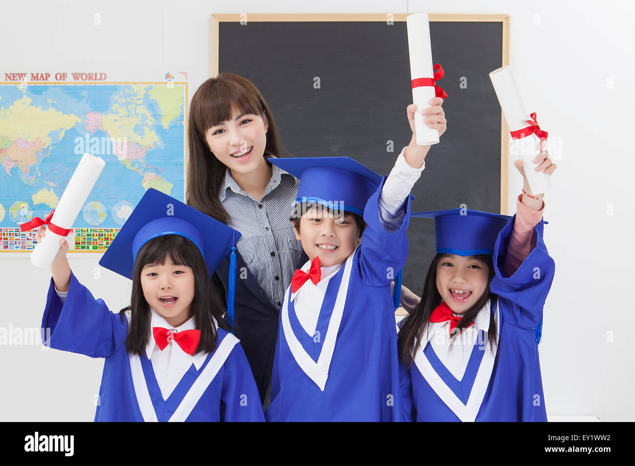 Junge Lehrer und Schüler mit Graduierung Kleider Diplom mit Lächeln zusammen halten, Stockfoto