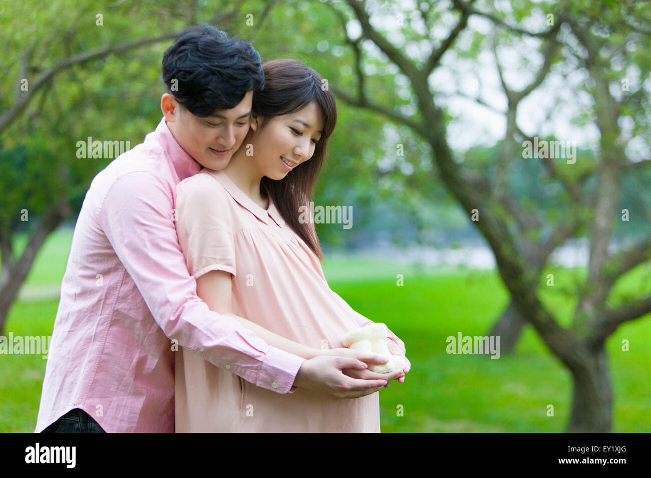 Junger Mann schwangere Frau umarmen und blickte mit Lächeln, Stockfoto